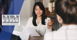 Woman in an interview gestering and looking at a resume with a smile